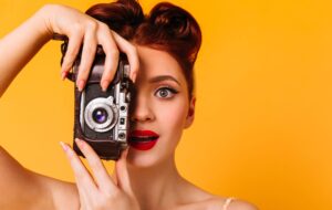portrait of amazed pinup woman with camera charming photographer with red lips taking pictures scaled 1